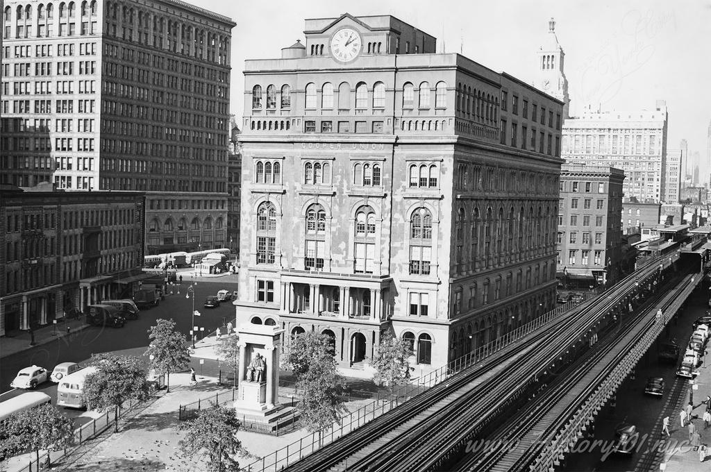 Photograph shows an elevated perspective of Cooper Union facing north and flanked along its east wall by the Third Avenue elevated railroad.